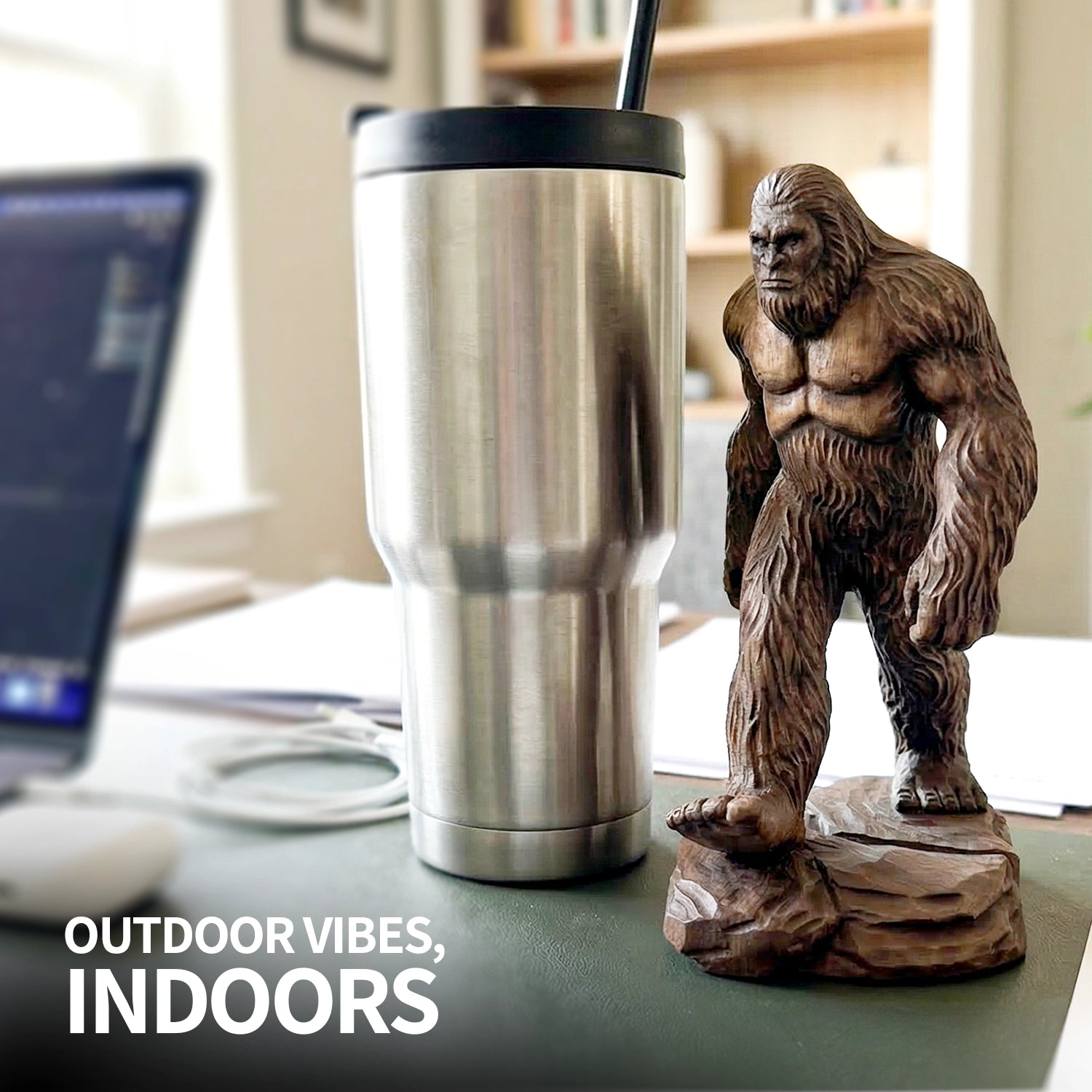 Sasquatch statue next to a stainless steel tumbler on a desk with 'Outdoor Vibes, Indoors' text.