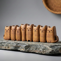 Row of wooden cat-shaped items on a stone surface with a neutral background